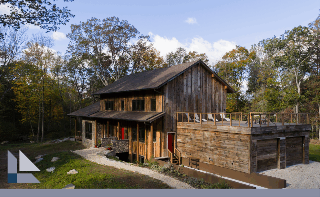 A house with wooden siding that displays BPC's legacy home building. It is. asunny day and trees surround the house