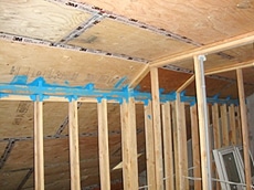 Plywood has been attached to the interior underside of the roof and attic trusses, and the joints have been taped to achieve an air-tight installation.